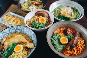 A variety of Asian dishes are displayed on a table, including bowls of ramen