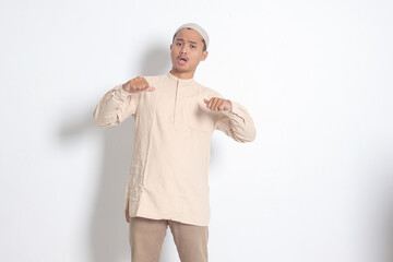 Portrait of attractive Asian muslim man in koko shirt showing thumb up, good job hand gesture....