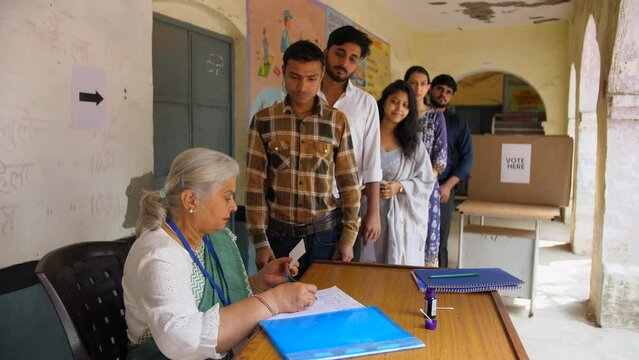 Government official checking the voter identification cards of the active voters for voting - general elections  state elections. Male and female citizens standing and waiting in line in the voting...