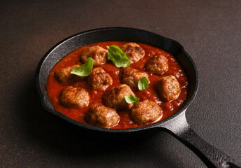 .Meatballs with tomato sauce and basil in a frying pan