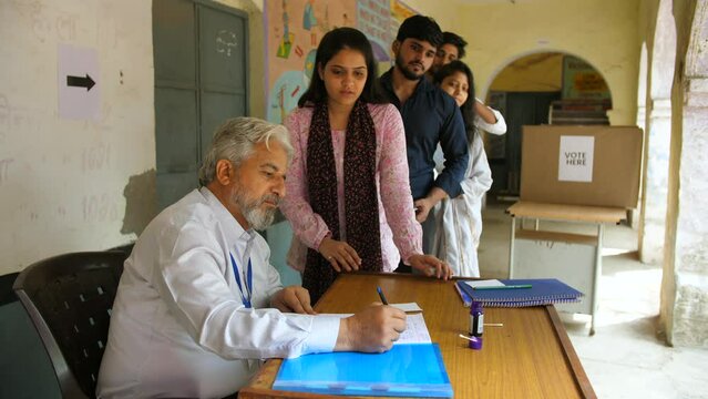 A government officer checking and putting ink on the index finger of an Indian female citizen - election process  first time voter. Young people standing in queue for voting - Indian election  gene...