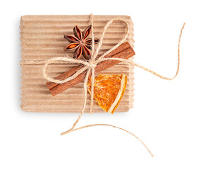 Top view of craft eco friendly gift box made of recycled carton or paper tied with thread bow decorated with dried orange fruit slice, cinnamon stick and anise star isolated on white background 