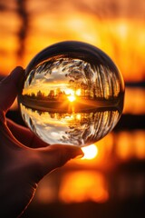 A person holding a glass ball with a sunset in the background. Ideal for travel and relaxation concepts