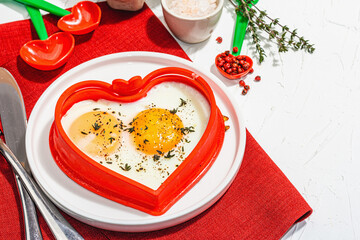 Heart-shaped fried egg served with toasted bread. Romantic art food idea for Valentine's breakfast