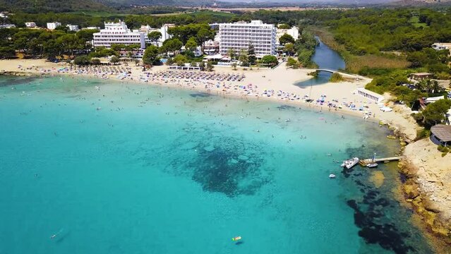 Crowded canyamel beach with turquoise waters on a sunny day, Mallorca, Spain, aerial view