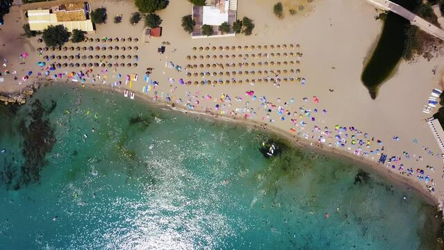 Playa de canyamel with umbrellas, bathers, and clear blue waters, sunny day, aerial view