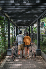 A couple walking in a trellis garden with their bikes.
