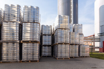 Large amount of aluminium beer kegs stacked on each other with euro palettes and wrapped around with vinyl foil.
