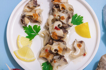 Pickled rapan meat with oil, spices and greens. Healthy seafood rich of omega