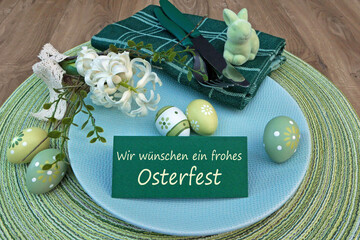 Tischdekoration zu Ostern mit Blumen,Ostereiern und einer Tischkarte mit dem Text Wir wünschen ein...