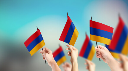 A group of people are holding small flags of Armenia in their hands.
