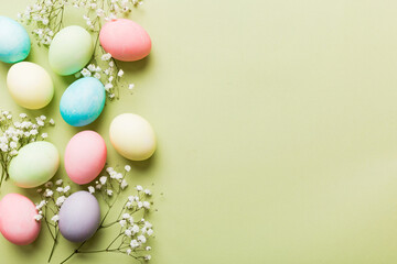 Happy Easter composition. Easter eggs on colored table with gypsophila. Natural dyed colorful eggs background top view with copy space