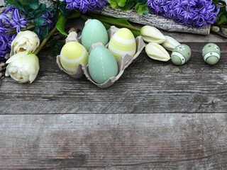 Farbenfrohe Osterdekoration mit Blumen auf schäbigem Holzbrett mit Platz für Text.