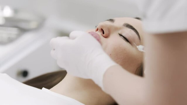 The procedure for lip augmentation and correction in a cosmetology salon. The specialist gives an injection to the patient's lips. Concept of cosmetology, cosmetic injections, and cosmetic surgery.