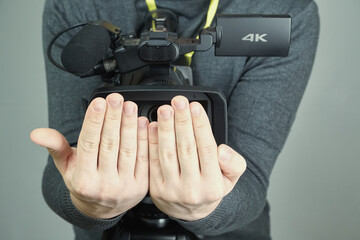 Two hands covering the lens of a video camera, peeping through closed palms, shooting not for the...