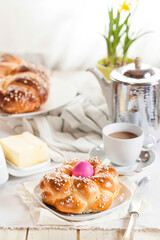 Braided Easter bread with pink egg, daffodil, coffee and butter