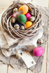 Colourful Easter eggs and quail eggs in rustic nest