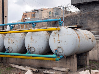 Fototapeta na wymiar Gas storage cisterns on background of residential buildings, selective focus. Construction site