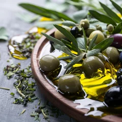 Foto op Plexiglas Extra virgin olive oil served with herbs, green and black olives over a grey background. © Emilian