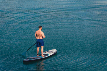 Fototapeta na wymiar man balancing on supboard paddling