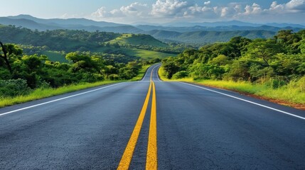 Naklejka premium A lone road cutting through a vibrant green valleys landscape