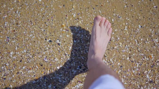 Barefoot person walking on the beach with waves washing over feet in 4k slow motion 120fps