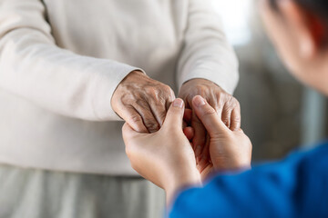 A female nurse caregiver holds hands to encourage and comfort an elderly woman. For care and trust...