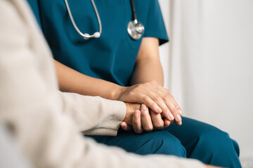 A female nurse caregiver holds hands to encourage and comfort an elderly woman. For care and trust...