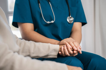 A female nurse caregiver holds hands to encourage and comfort an elderly woman. For care and trust in nursing homes for people of retirement age Caregiver helping elderly woman provides medical advice