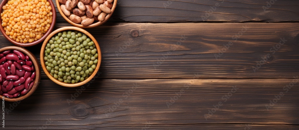 Poster assorted beans and lentils displayed in bowls on wooden background with copy space