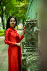 Obraz premium Woman wearing traditional Vietnamese ao dai walking on the road of flying tamarind leaves.Portrait of woman wearing black sunglasses while standing behind friend.