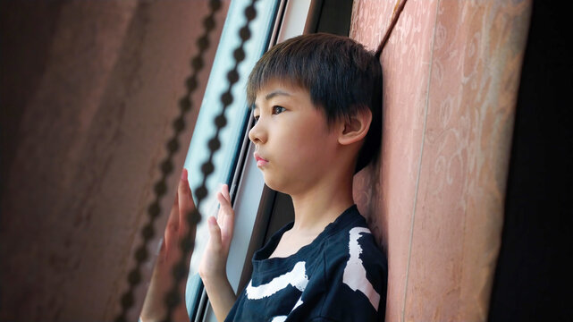 Portrait of Asian Boy Looking out a Daytime Window.