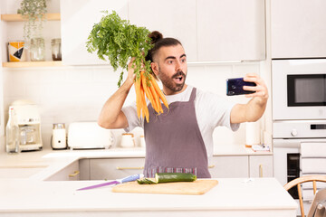 long-haired man cooking at home looking at tablet, chopping vegetables, taking selfie photos,...