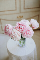 bouquet of soft pink peonies against a background of vintage furniture, photo in pastel colors
