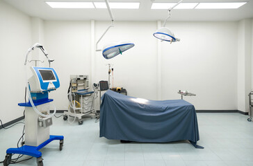 A typical operating room in a hospital with surgical light overhead for providing bright, directional lighting to the surgical team during procedure. The operating table is at the center of the room.