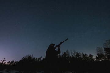 A soldier with a night vision device and a rifle with a silencer against the background of the...