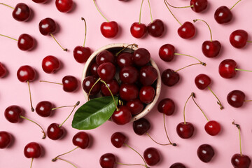 Ripe cherry fruits in a bowl on a pink background