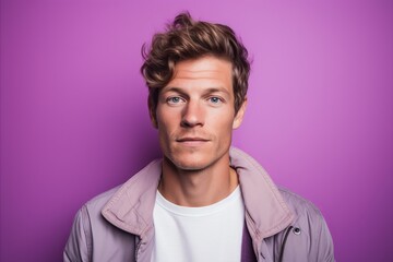 Portrait of a handsome young man in casual clothes on a purple background.
