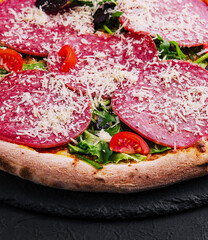 Delicious pizza with salami, arugula and tomatoes