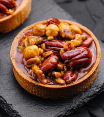 Tartlet with caramelized nuts on black table