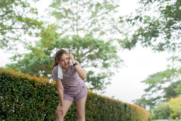 Asian woman taking a moment to catch her breath after tired workout in park