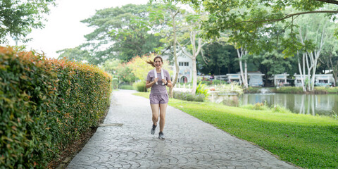 Woman active Asian woman in sportswear listening to music while running or jogging in the park in the morning