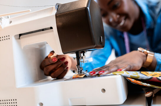 Female fashion tailor with sewing machine working on dress design in her workshop.