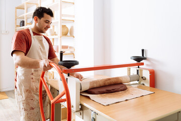 Focused man working with slab roller in workshop