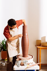 Artisan using wooden tool to make clay vase in pottery workshop