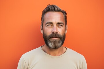 Portrait of a handsome man with a beard on a orange background - obrazy, fototapety, plakaty