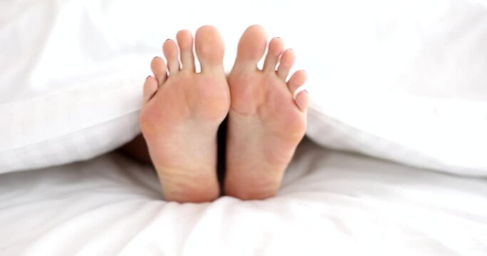Closeup of woman staggers legs in bed. Stretching legs in bed
