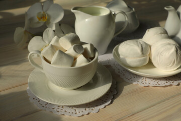 Spring breakfast with marshmallow, coffee and milk. Flatlay with food and flower in white color