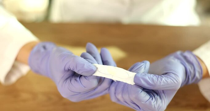 Doctors gynecologist in rubber gloves open rectal suppositories closeup. Treatment of sexually transmitted infections