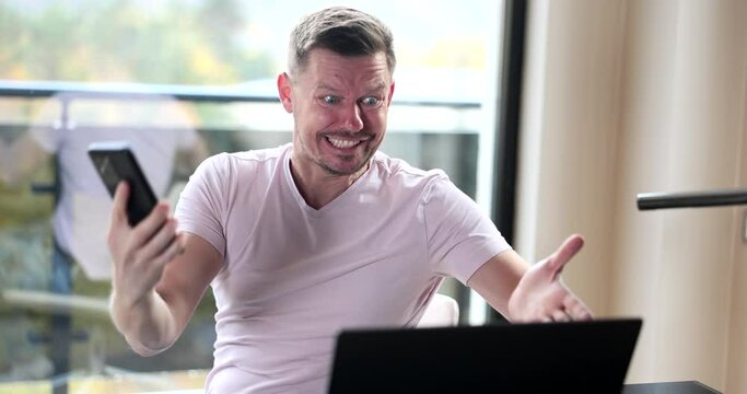Impulsive angry man screaming into phone and laptop. Bad news error report stock market crash